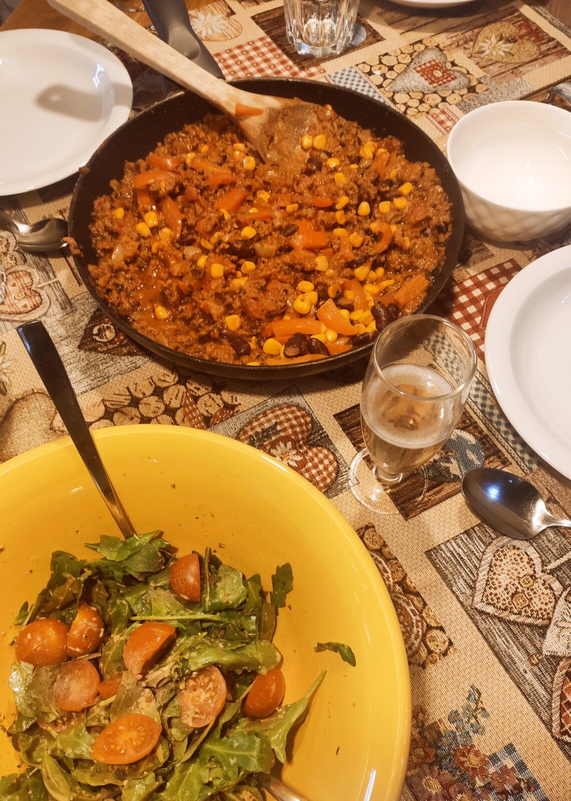 Eine Pfanne mit Chili sin Carne und eine Schüssel Salat stehen auf einem Tisch.